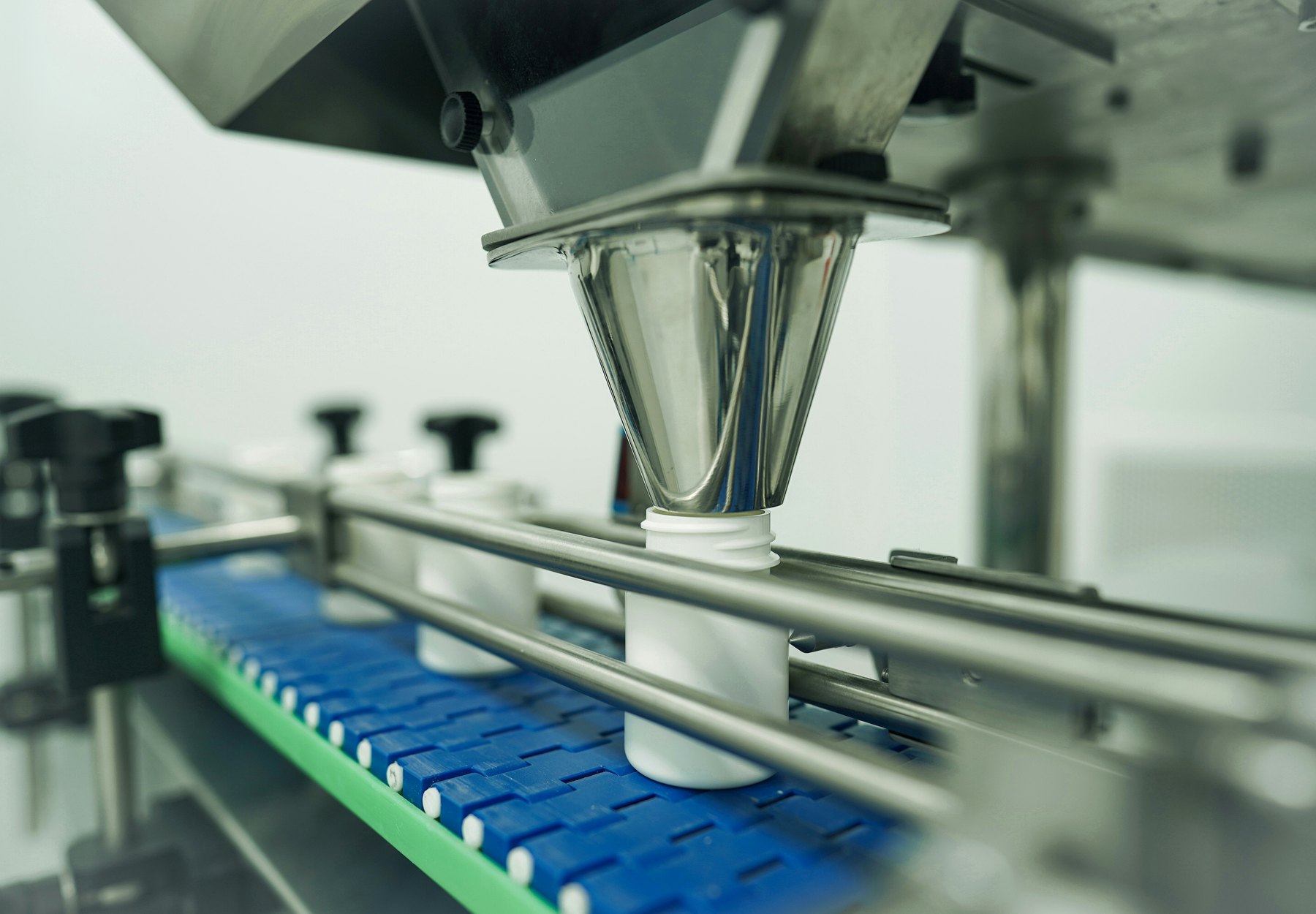 Close-up filling head and conveyor detail on automated packaging machinery